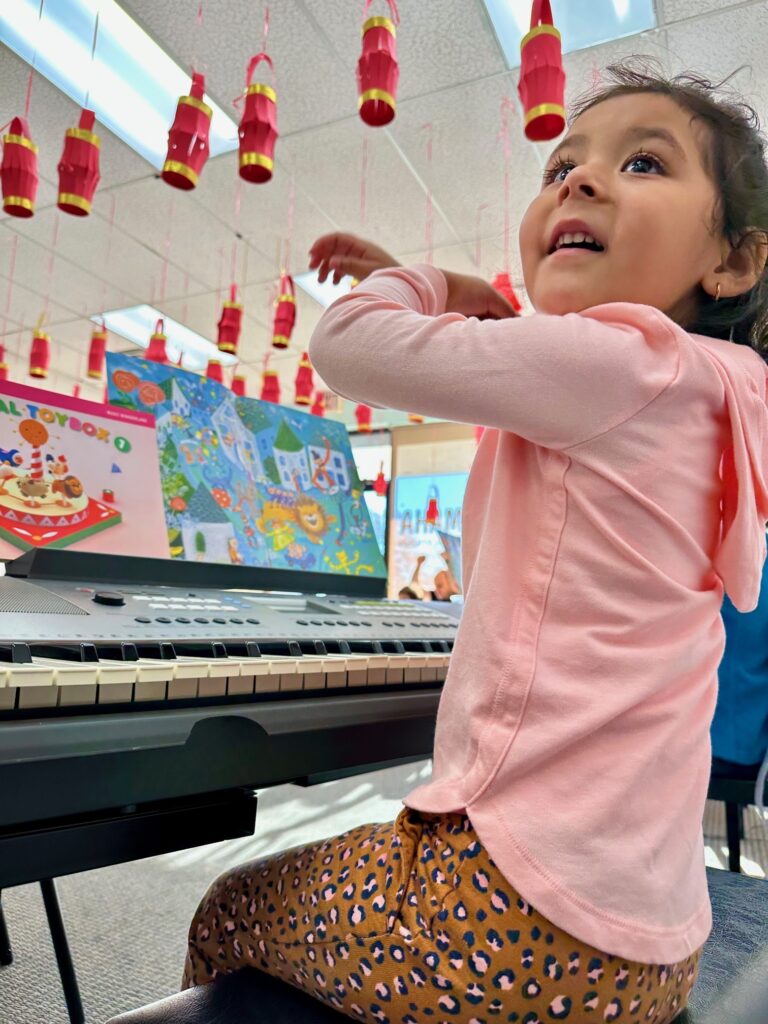 3 year old child enjoying music in a keyboard class